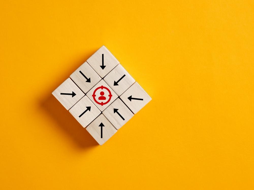 Arrows on Wooden Cubes Pointing Towards the Focused Target Customer.